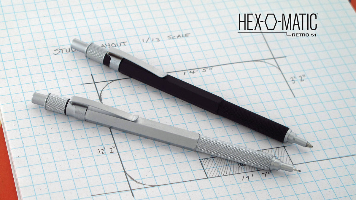 black Hex-o-matic pen and silver Hex-o-matic pencil on top of graph paper